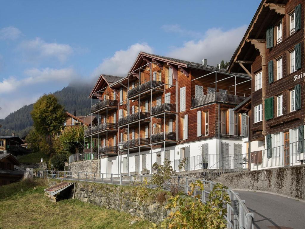 a large building on a hill next to a river at Apartment Breithorn Residence Apt-3 by Interhome in Wengen