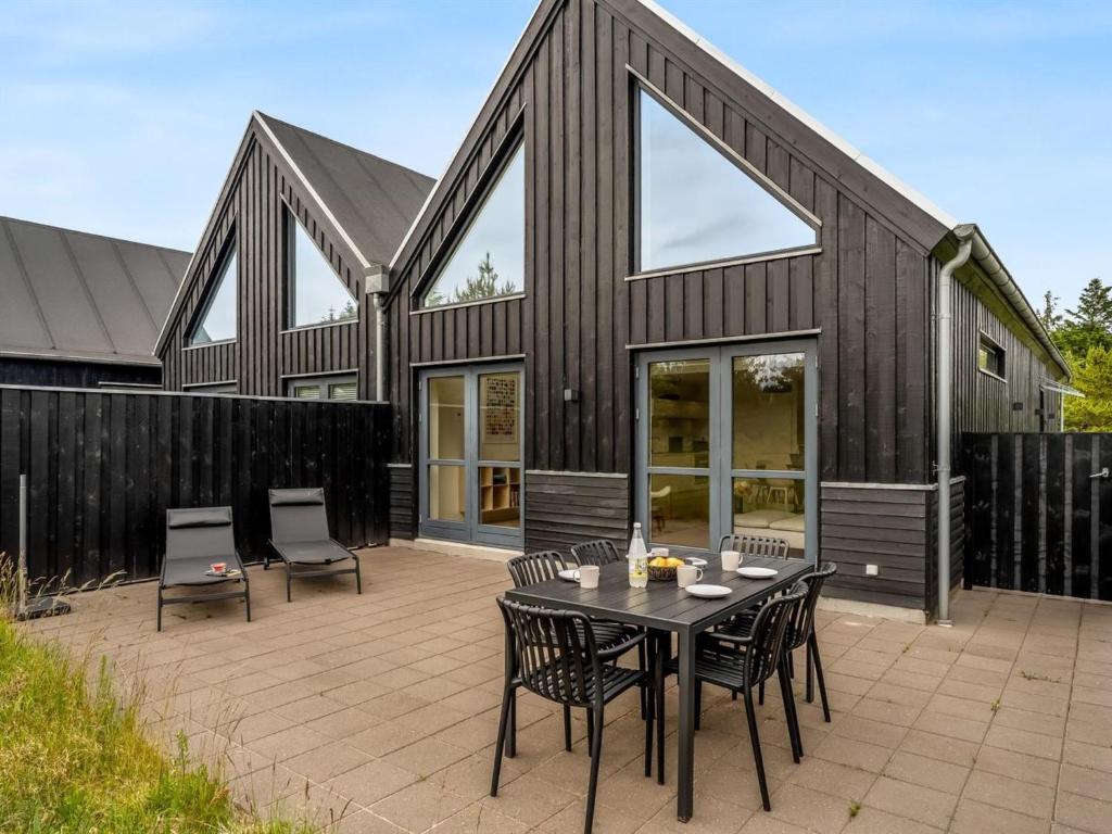 a black house with a patio with a table and chairs at Holiday Home Anelle - 2-5km from the sea by Interhome in Blokhus