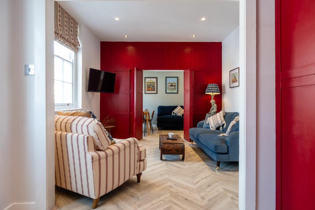 a living room with two chairs and a red wall at Stunning High Street Hideaway in Cheltenham in Cheltenham