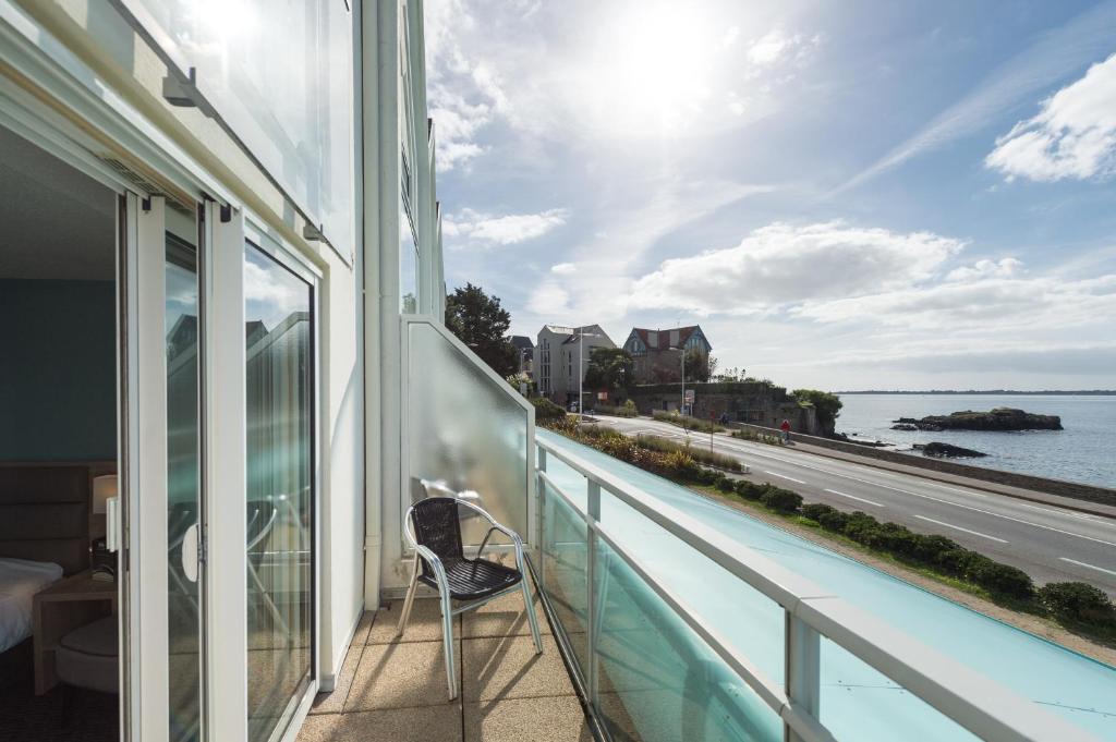 a balcony with a chair and a view of the water at Hôtel de l'Océan Concarneau in Concarneau
