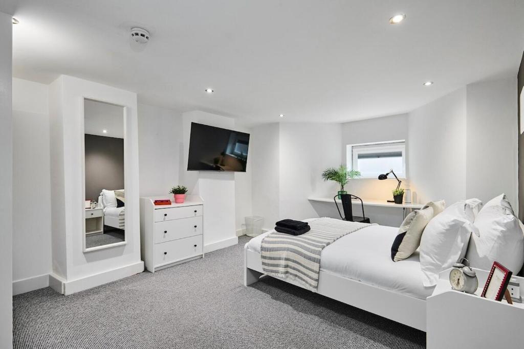a white bedroom with a bed and a tv at Kendal Lane Apartments in Central Station