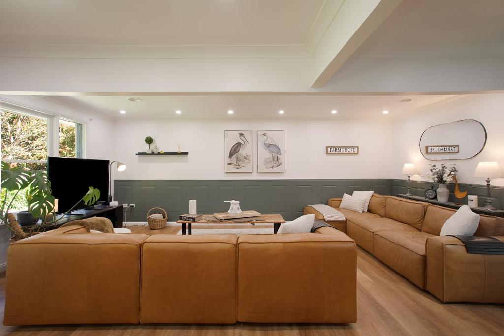 - un salon avec deux canapés bruns et une télévision dans l'établissement Highlands Heart Cottage, à Bowral