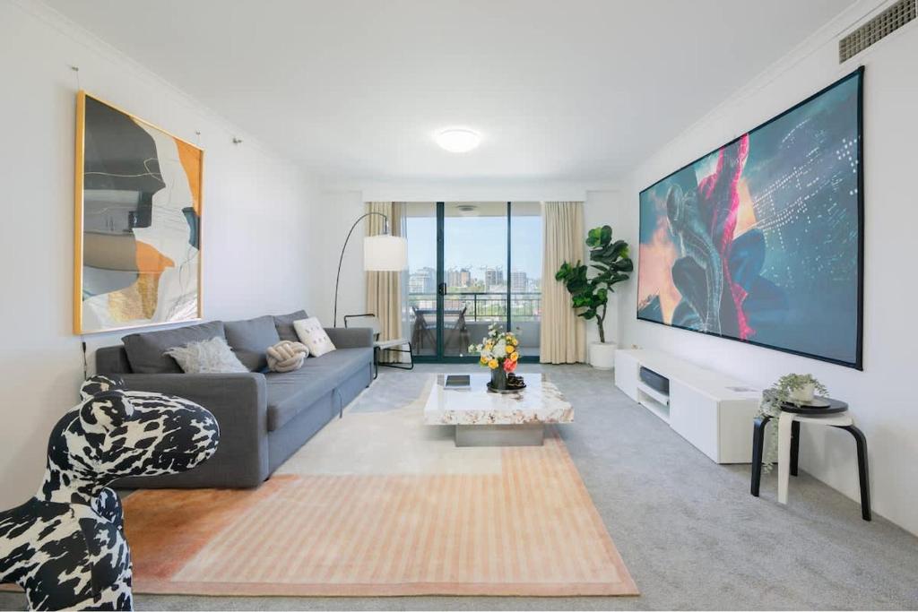 ein Wohnzimmer mit einem Sofa und einem großen TV in der Unterkunft The Arcadia in CBD w Parking Desk Gym Pool in Sydney