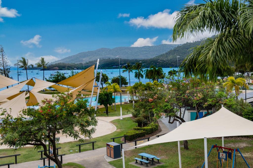 ein Park mit weißen Sonnenschirmen und einem Spielplatz in der Unterkunft Bella Isola in Airlie Beach