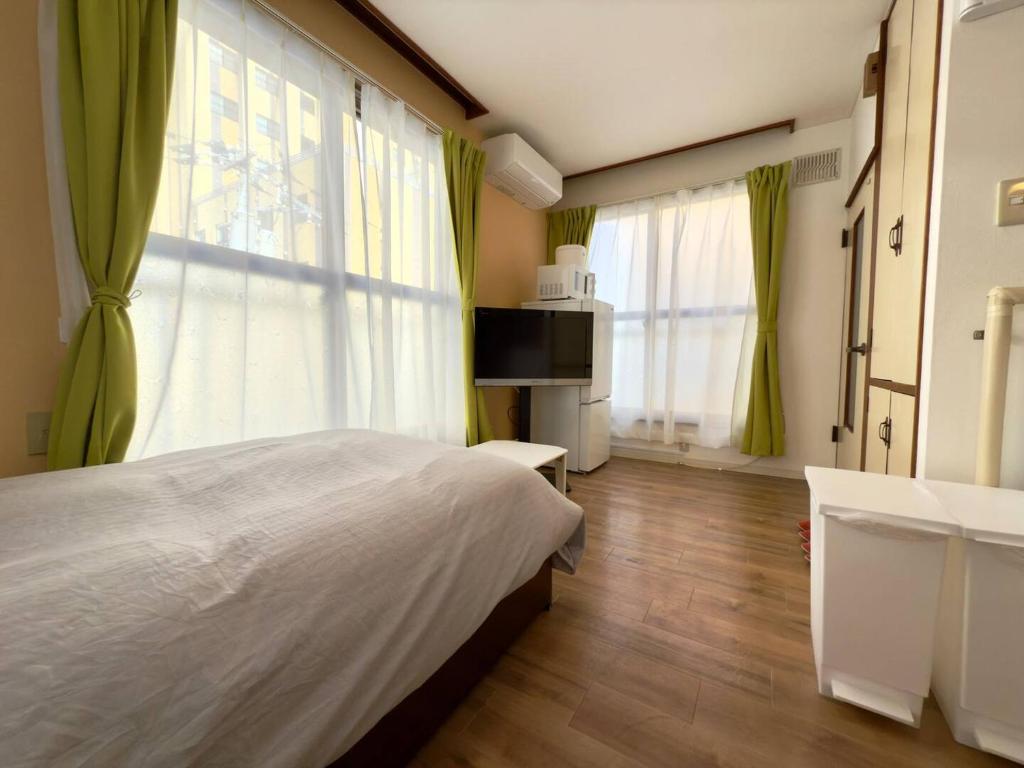 a bedroom with a large bed and green curtains at 2-6大通駅まで地下鉄で4駅の場所で美室のリフォーム済みアパートメント in Sapporo