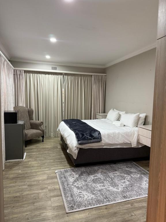 a bedroom with a large bed and a chair at Bee Boutique Lodge in Nelspruit