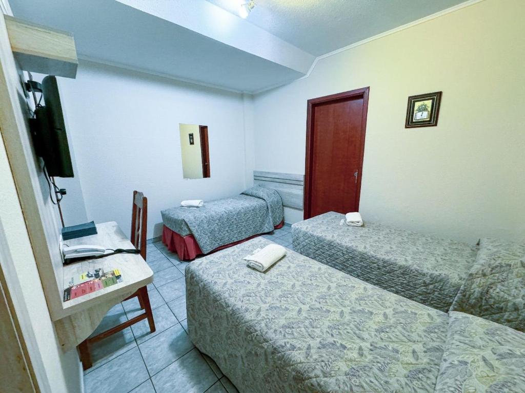 a hotel room with two beds and a television at Colonial Hotel in Campo Grande