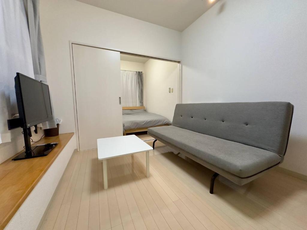 a living room with a couch and a tv at 401好立地札幌駅徒歩7分と大通駅徒歩6分で都心を満喫で綺麗な部屋で快適が生活が実現 in Sapporo
