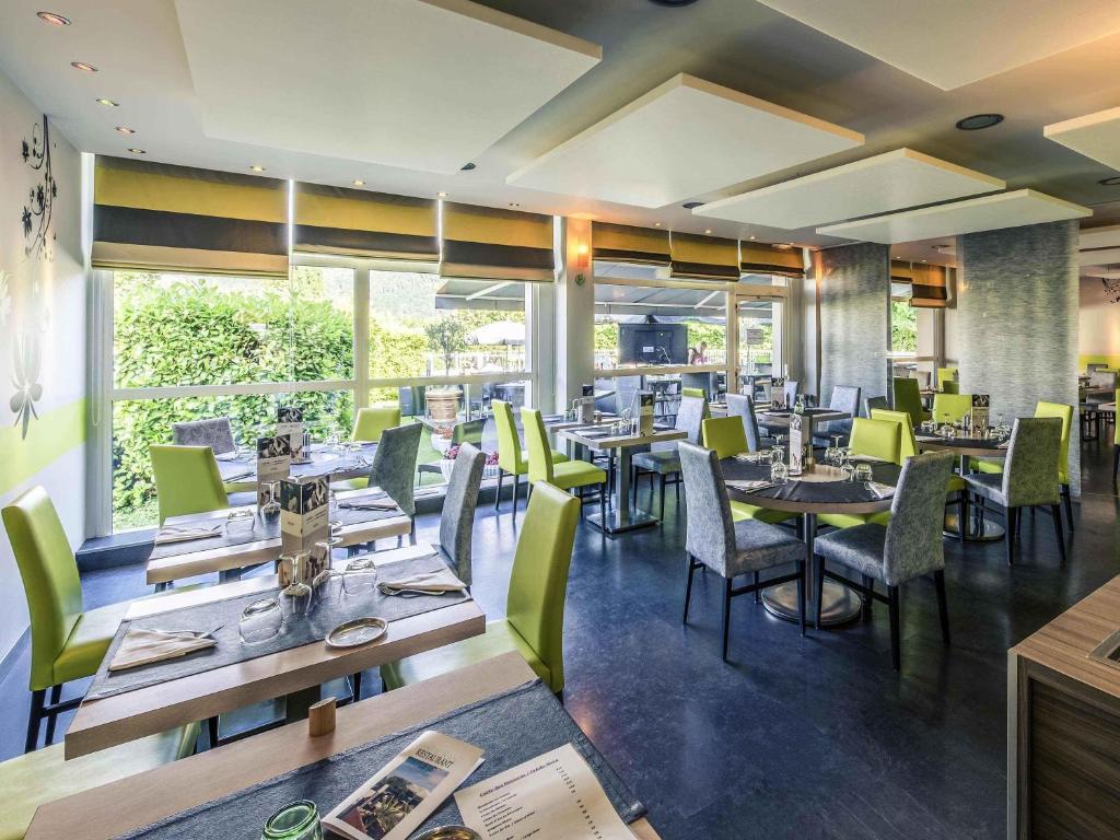 a dining room with tables and chairs and windows at Mercure Annecy Sud in Annecy