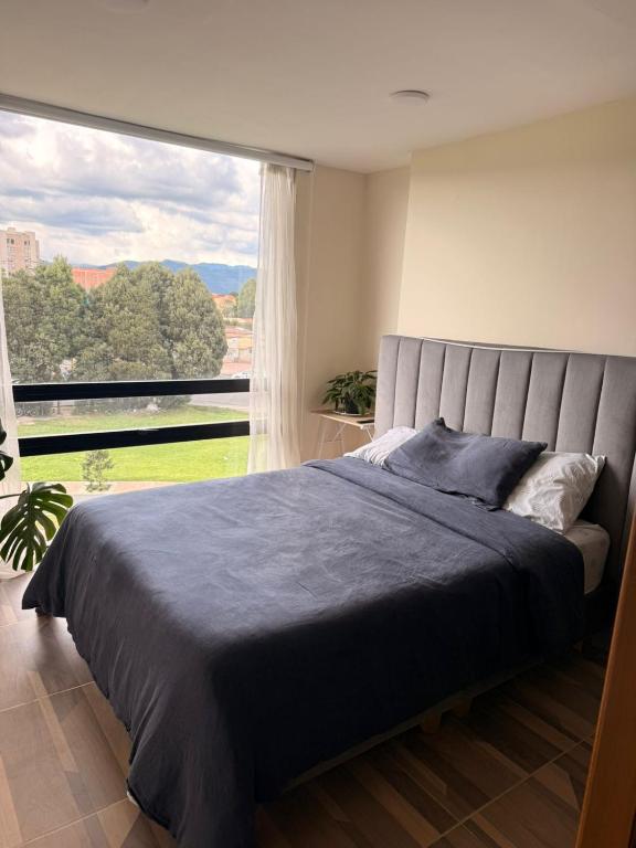 a bed in a bedroom with a large window at Apartamento Suite Chía Solar 228 in Chía