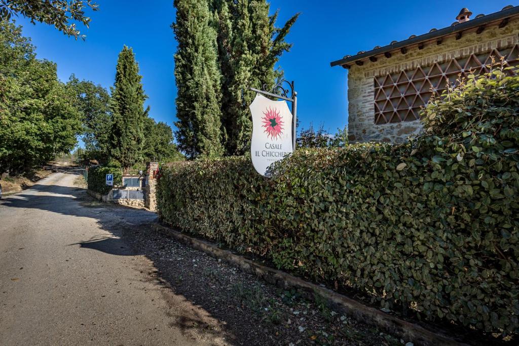 een bord op een heg voor een gebouw bij Casale Il Chicchero in Castel San Gimignano