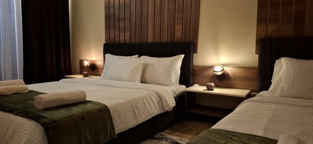 a hotel room with two beds and two lamps at Grand Albi Apartament in Gjakove