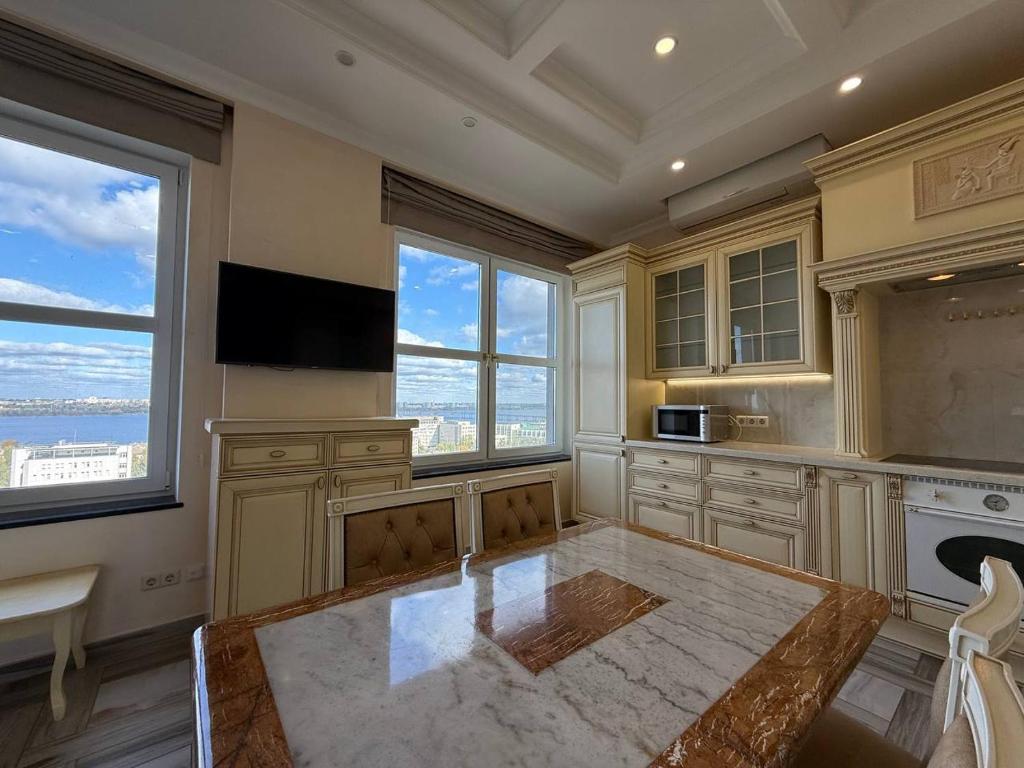 uma grande cozinha com uma mesa e algumas janelas em Дельмар Люкс em Dnipro