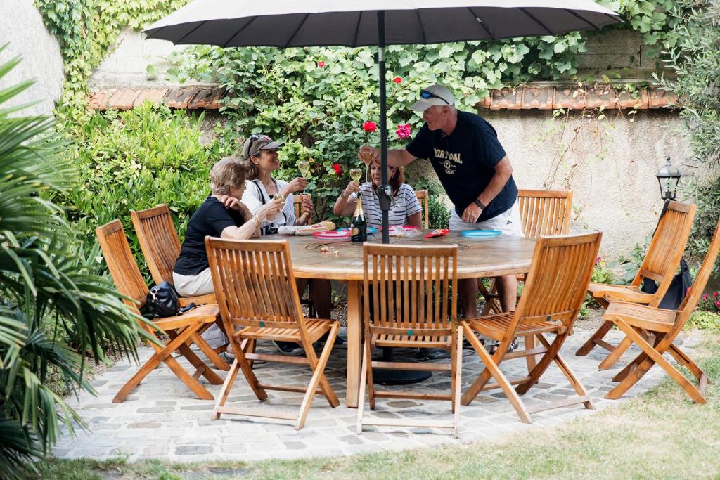 eine Gruppe von Menschen, die unter einem Schirm um einen Tisch sitzen in der Unterkunft La Poterne l Maison d'hôtes à Epernay in Rouen