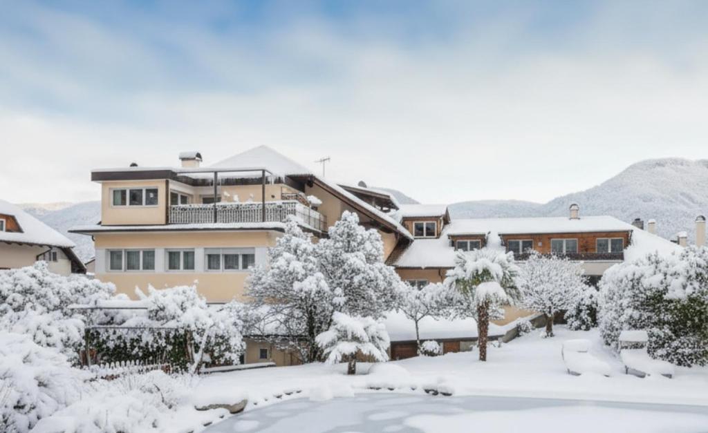 een gebouw bedekt met sneeuw met bomen en struiken bij Kreuzwegerhof Nals - Historic Nature Stay with Pool near Meran & Bozen in Nalles