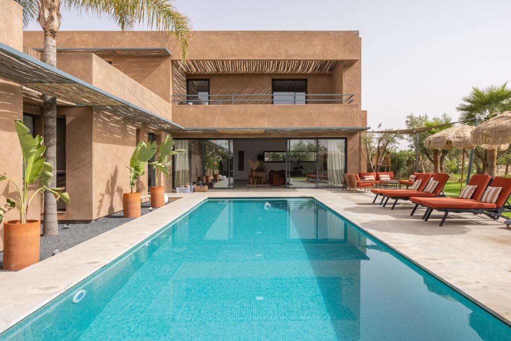 a swimming pool in front of a house at Modern villa - 4 luxury suites - Golf Amelkis - Marrakech in Marrakech
