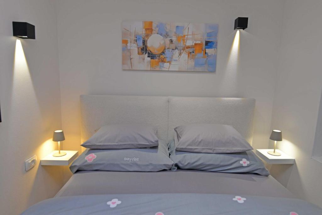 a bed with two pillows and a painting above it at LunaStela in Veli Lošinj
