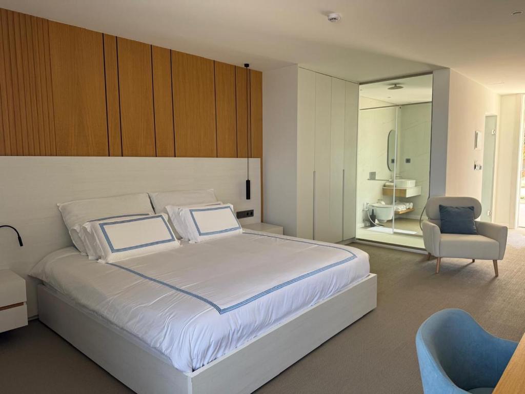 une chambre avec un grand lit blanc et une chaise dans l'établissement Blue Ocean Tofo Hotel, à Praia do Tofo