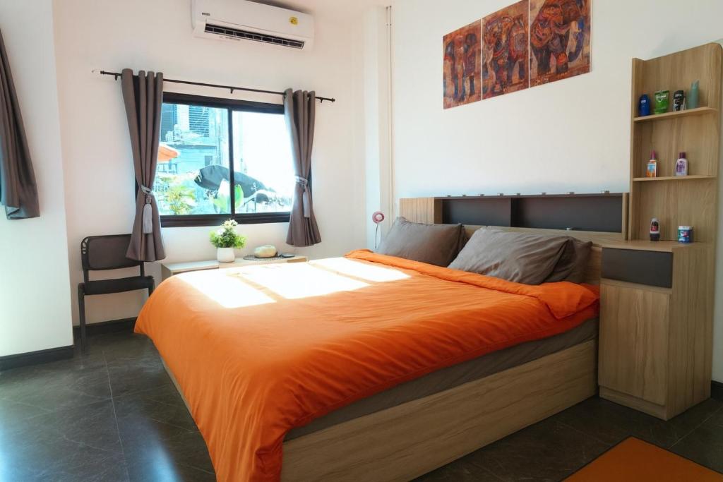 - une chambre avec un lit et une couette en orange dans l'établissement London House Phuket, à Kata Beach