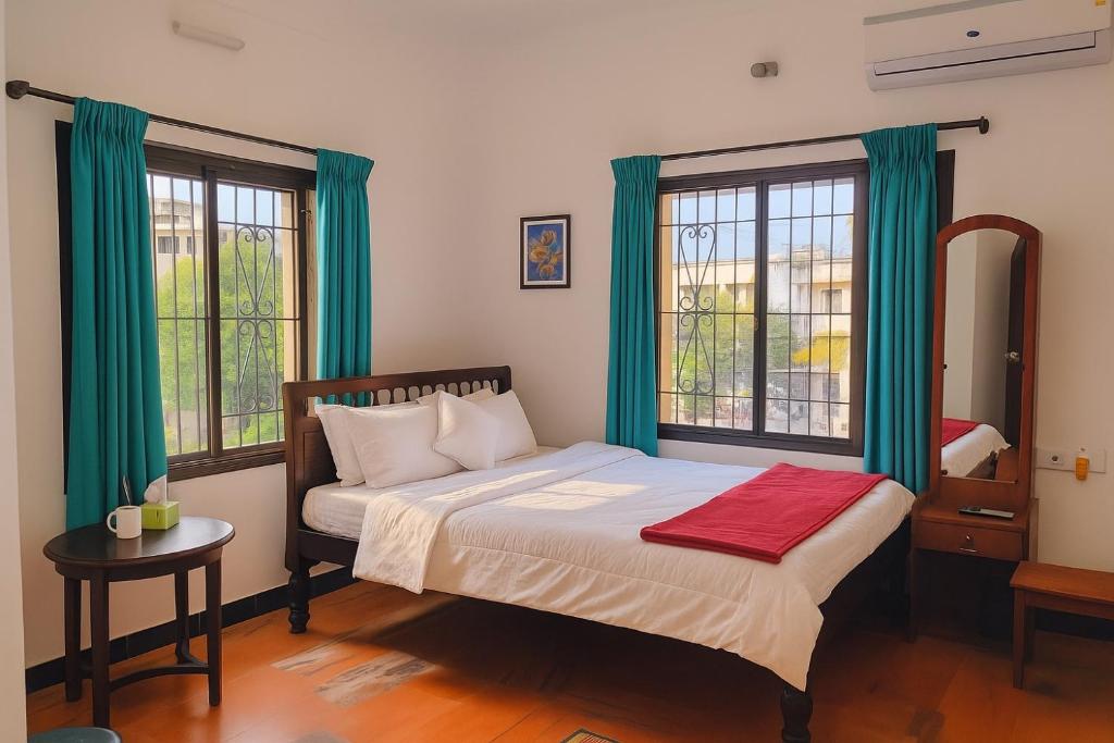 PūrnānkuppamCeleste Luxury Bungalow的一间卧室配有一张带绿色窗帘和窗户的床。