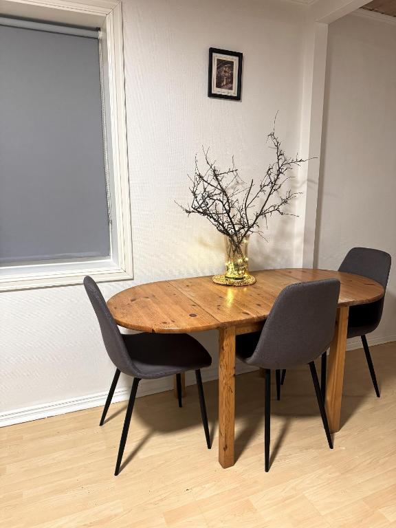 a dining room table with chairs and a vase with flowers at Norway Lights center of Bodo near Train station and Aeroport in Bodø