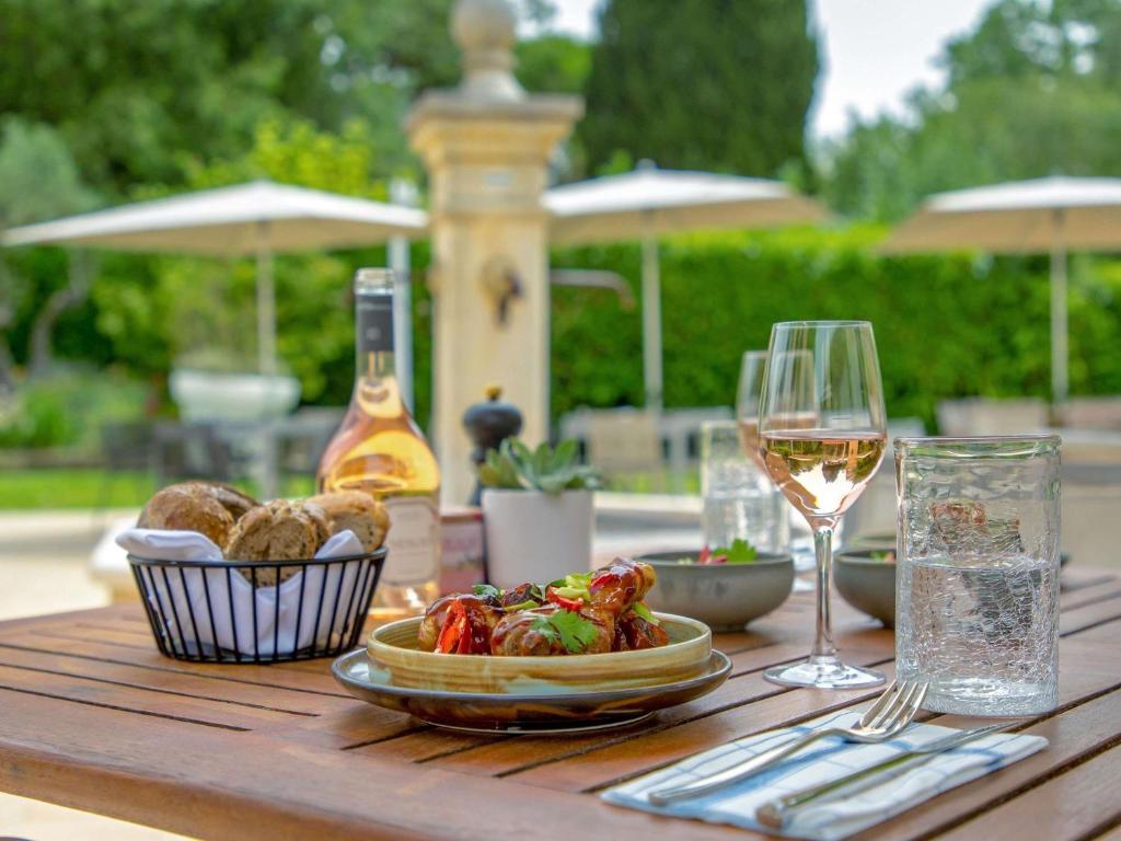 a table with a glass of wine and a plate of food at Novotel Aix-en-Provence Pont de L'Arc in Aix-en-Provence
