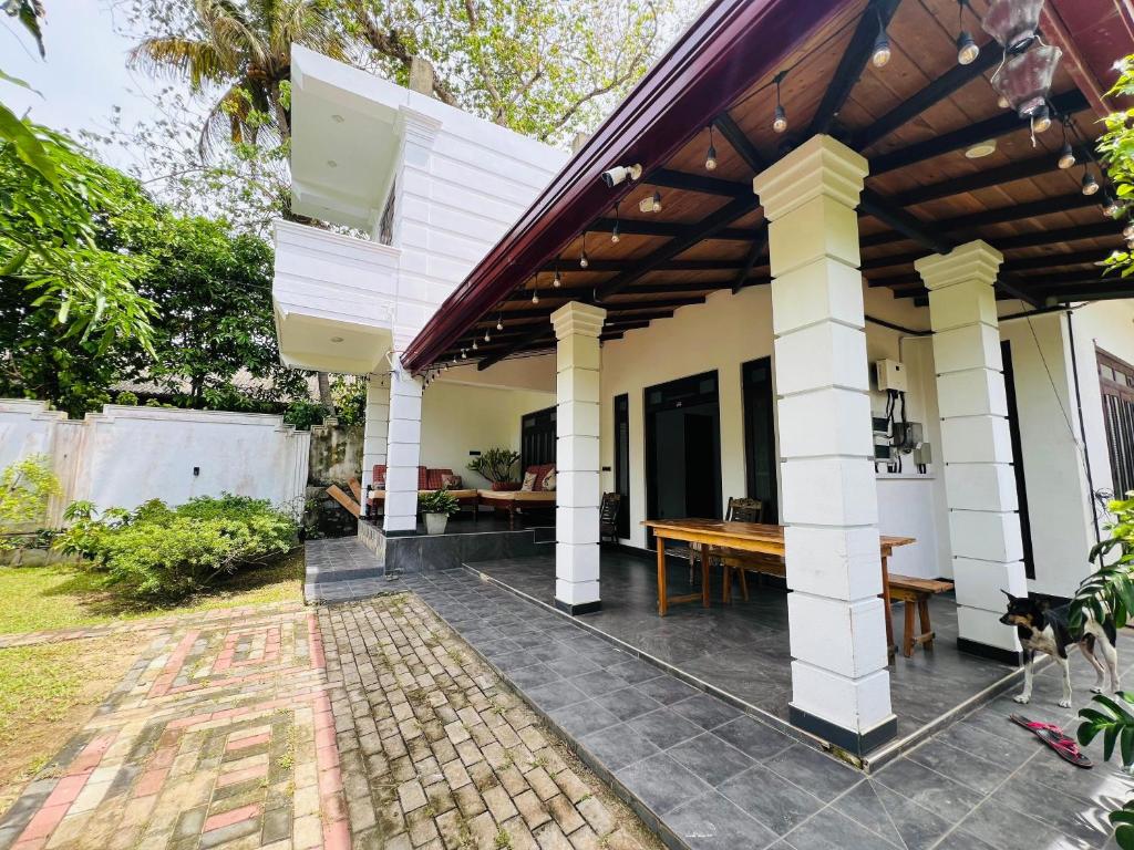 a house with a wooden table on a patio at Kuchu surf hostel in Weligama