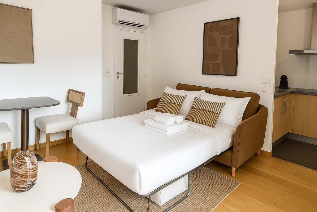 ein Wohnzimmer mit einem weißen Bett und einem Tisch in der Unterkunft Courbevoie Studio terrasse situe pres de Paris in La Garenne-Colombes
