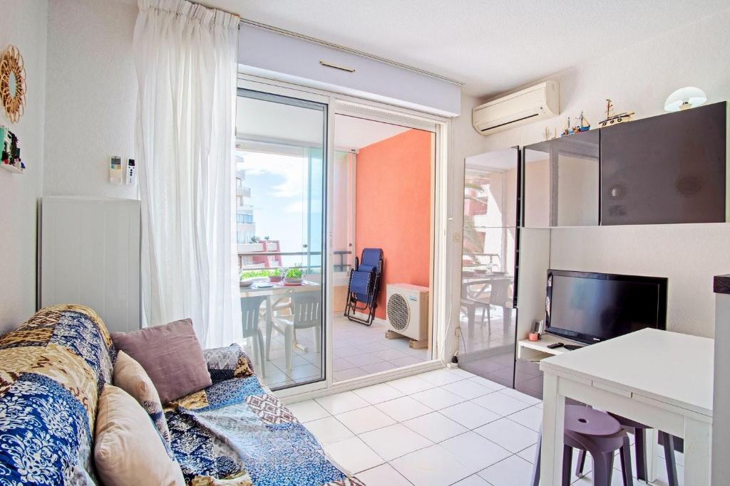 ein Wohnzimmer mit einer Couch und einem Tisch und einem Fernseher in der Unterkunft Chez Juan - T3 Climatisé - Piscine et parking in Sète