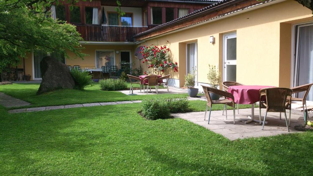 een patio met een tafel en stoelen in een tuin bij Ferienwohnungen Vidoni in Bodensdorf