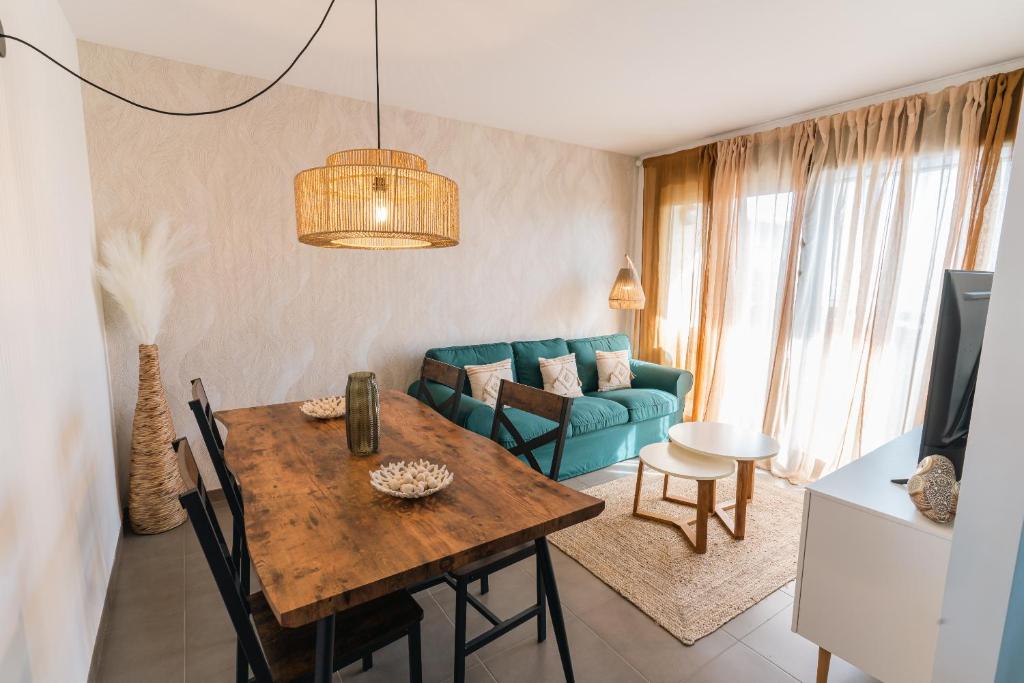 Una sala de estar con una mesa y un sofá azul. en Bella Palace, Apartamento acogedor junto al mar, en Alcanar