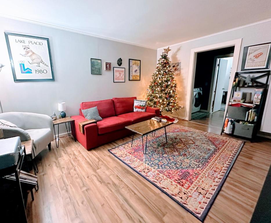 un salon avec un canapé rouge et un sapin de Noël dans l'établissement Yinzer House - Whiteface Lake Placid Arcade Fun, à Jay