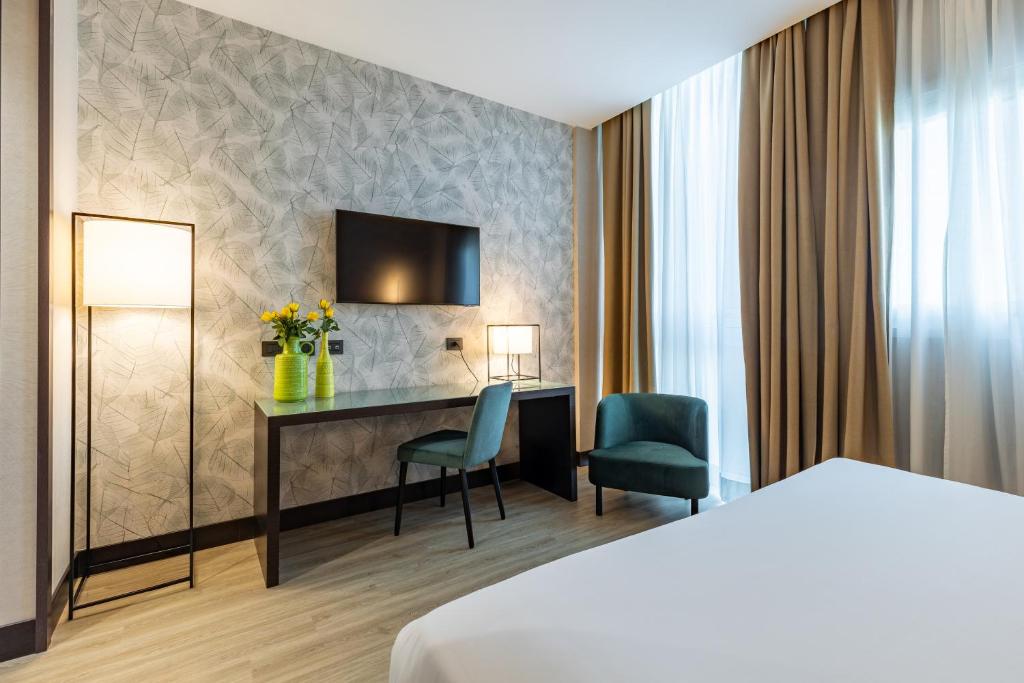 a hotel room with a bed and a desk and chairs at H2C Hotel Milanofiori in Assago