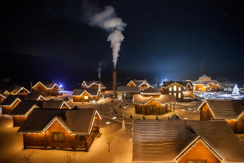 un grupo de casas cubiertas de nieve por la noche en TAOR Karpaty Resort & Spa, en Skhidnytsya