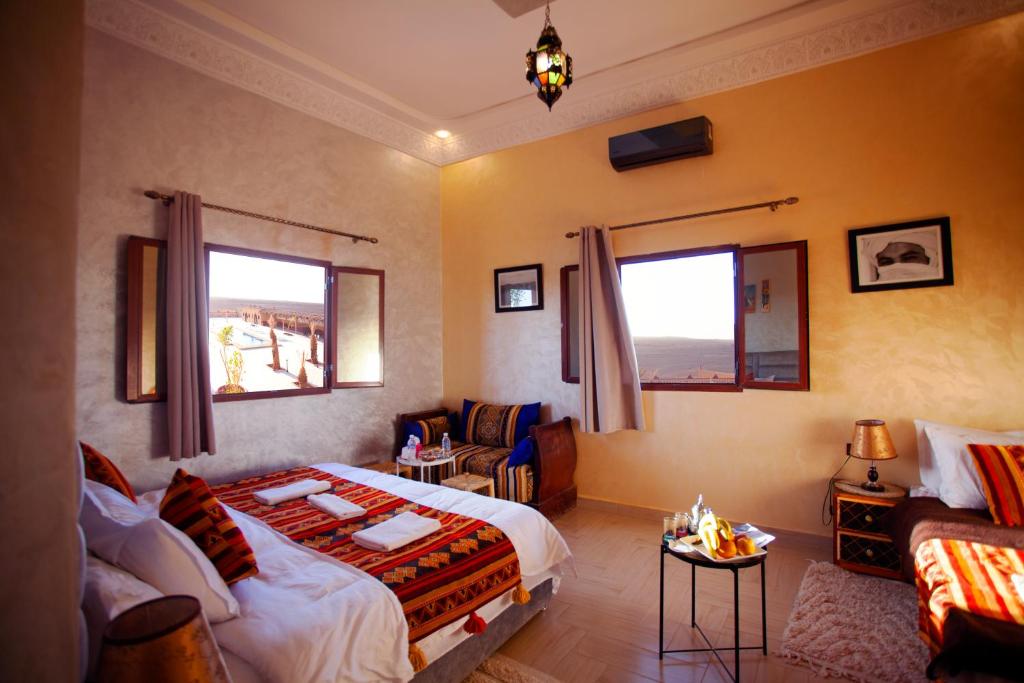 a bedroom with a bed and a couch and a table at Hotel Berber Palace Merzouga in Hassilabied
