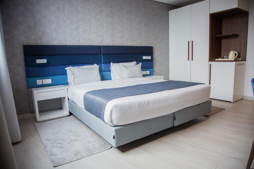 マプトにあるWL Hotel Maputo Executiveのベッドルーム1室(大型ベッド1台、青いヘッドボード付)