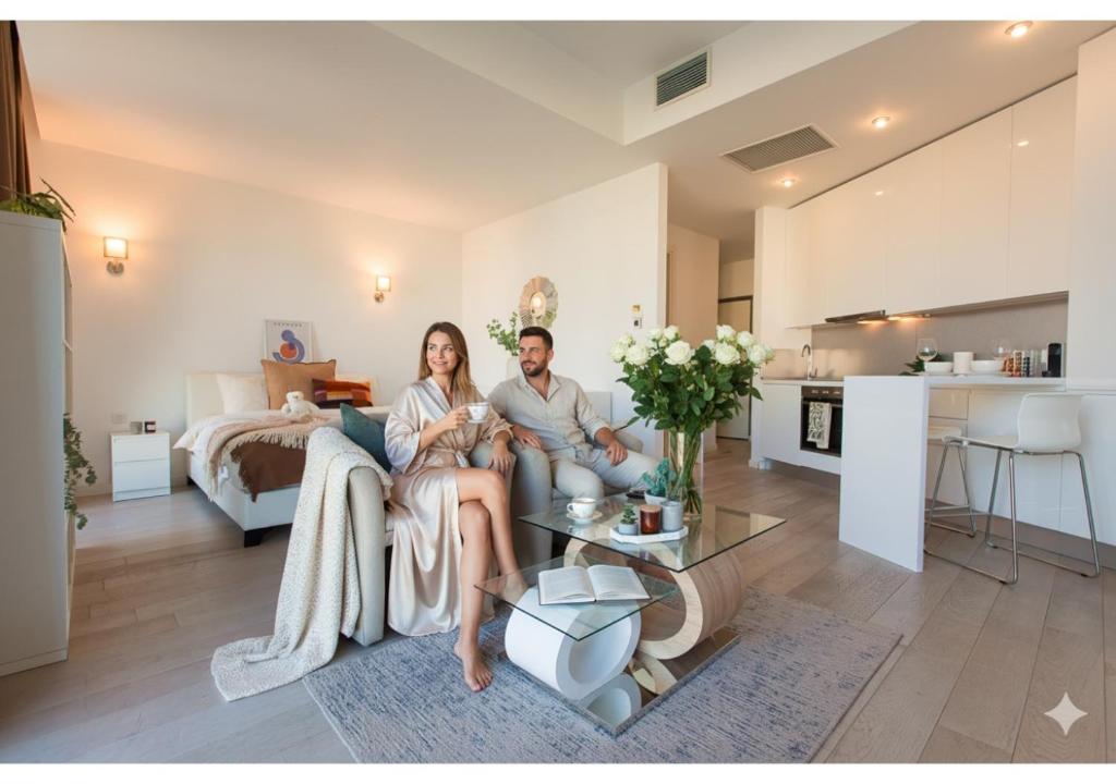 a man and woman sitting on a couch in a living room at Premium Studio Apartment in Herastrau with City View in Herăstrău
