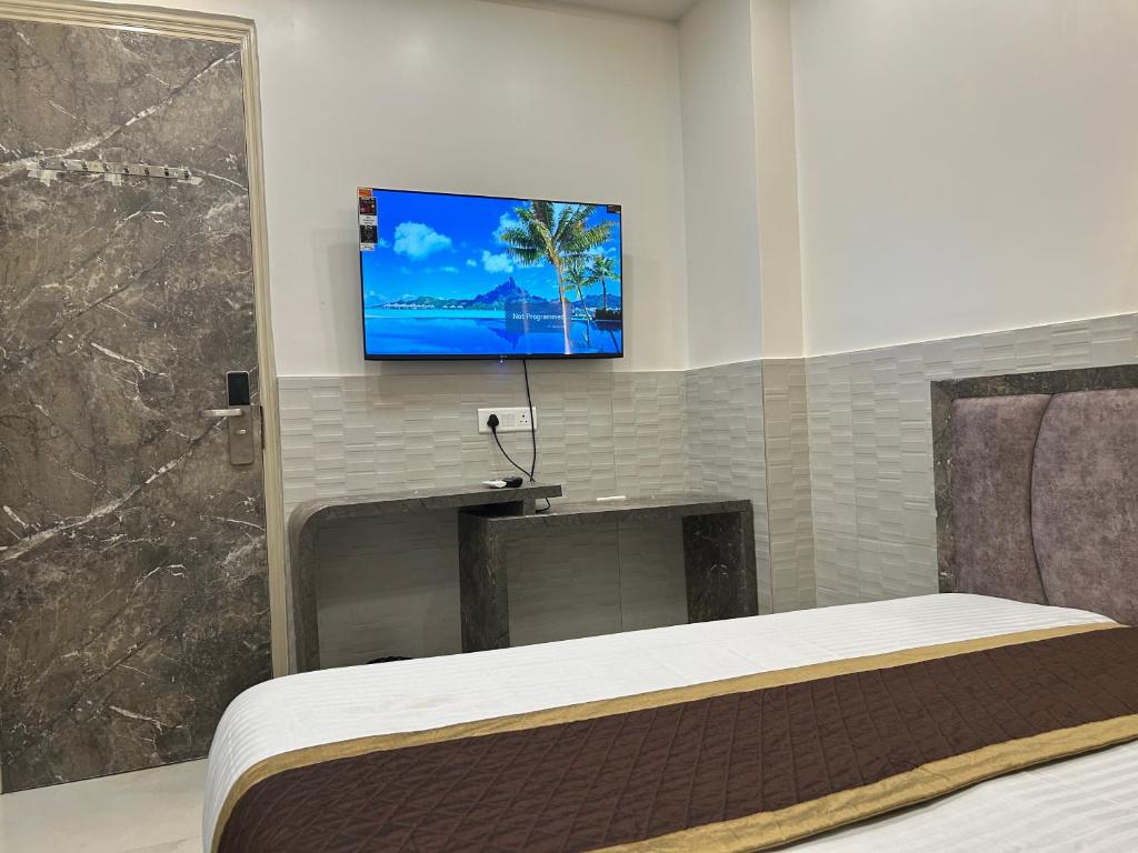 a bedroom with a bed and a tv on a wall at Hotel Shree Guru Plaza 3 Minute Walking Distance From New Delhi Railway Station in New Delhi
