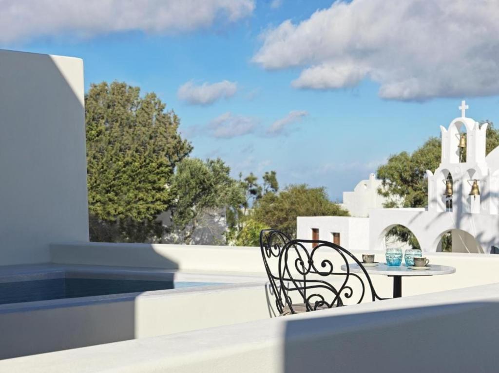 a table and chairs on the roof of a building at Notia Suite, Jacuzzi, Imerovigli in Imerovigli