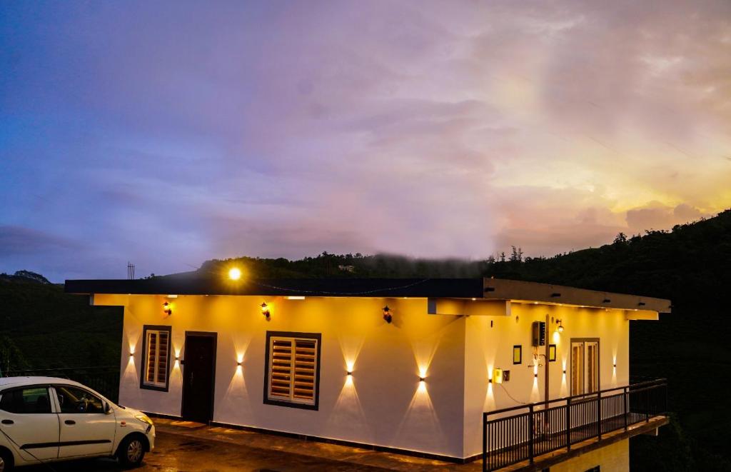 a white house with a car parked in front of it at Sravan Villa in Vagamon