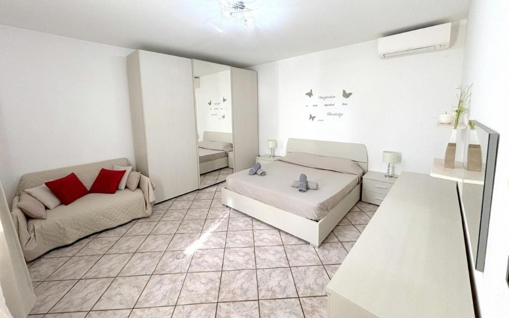 Cette chambre blanche dispose d'un lit et d'un canapé. dans l'établissement Fontana Comfort Apartment, à Castelnuovo del Garda