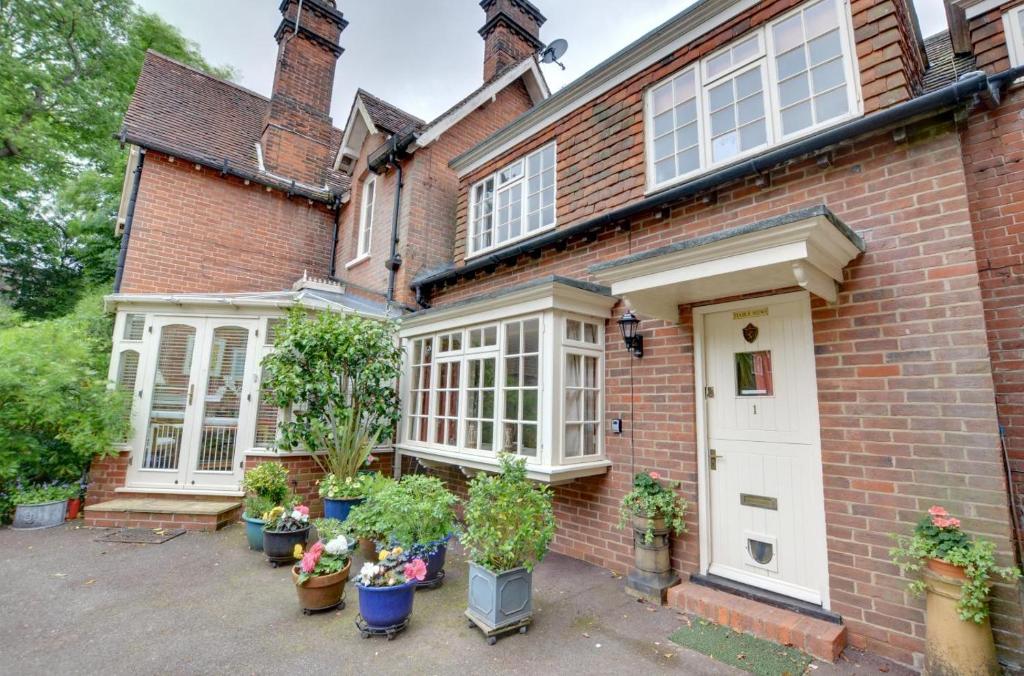 ein Backsteinhaus mit Topfpflanzen davor in der Unterkunft Stable Mews Cottage in Royal Tunbridge Wells