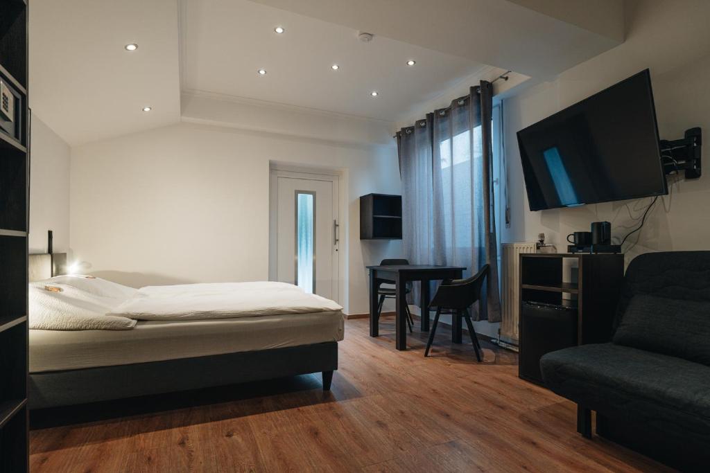 a bedroom with a bed and a desk and a tv at Hotel Restaurant Latio in Cologne