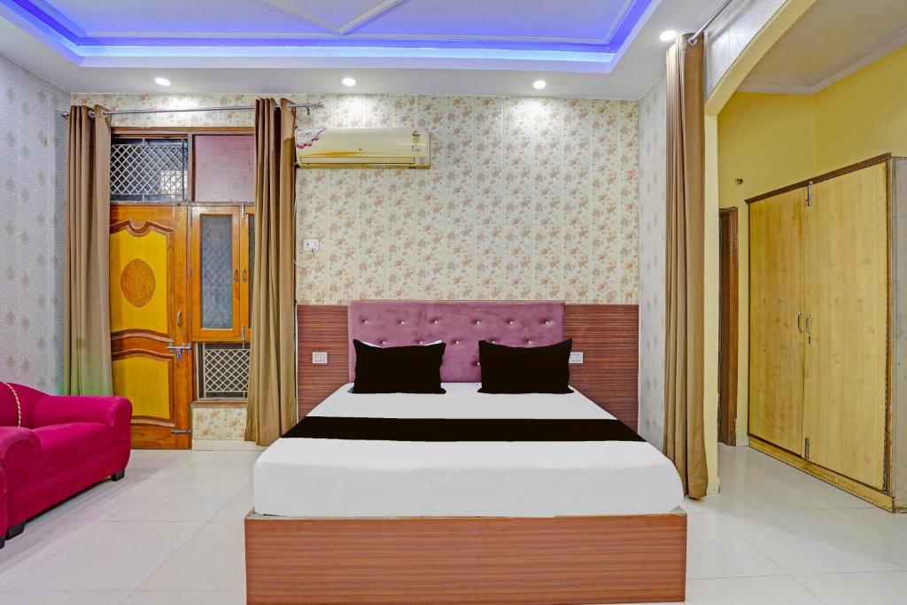 Un dormitorio con una cama grande y un sofá rosa. en Hotel O Laresa, en Ghaziabad
