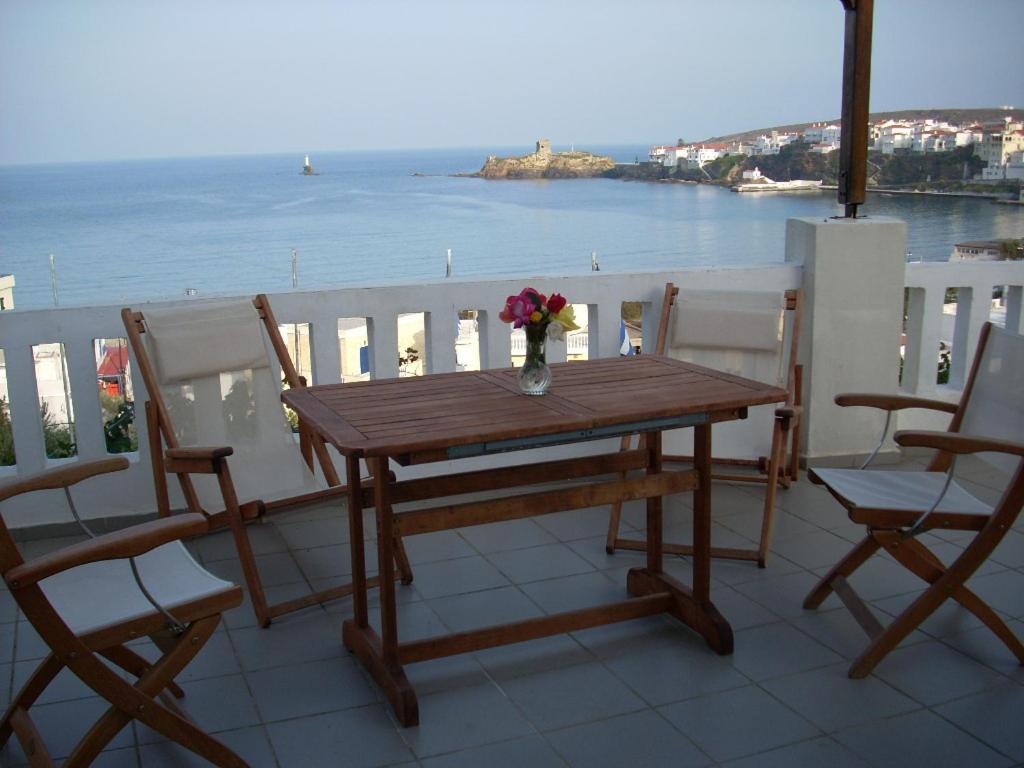 a wooden table with a vase of flowers on a balcony at Vassiliki Studios in Andros