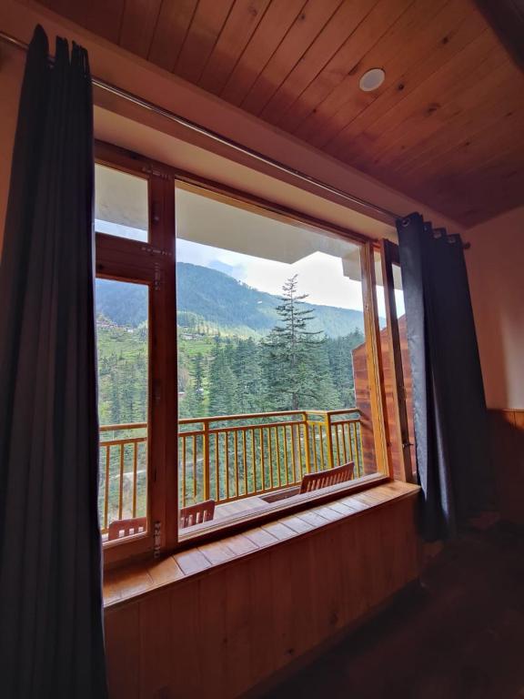 a window with a view of a mountain view at The Woodpecker Inn Jibhi in Jibhi