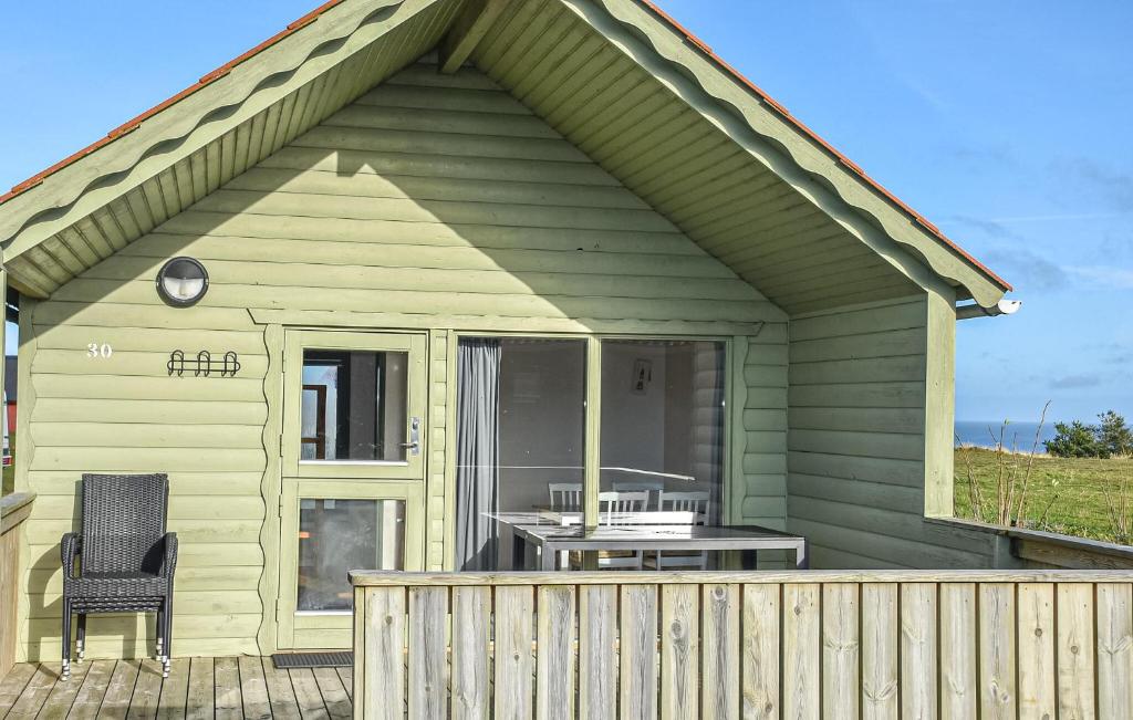 a green house with a table and a chair on a deck at Cozy Home In Hanstholm With Private Swimming Pool, Can Be Inside Or Outside in Pugdal