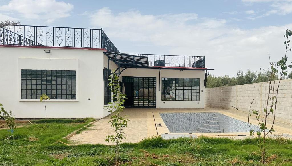 a white house with a swimming pool in front of it at Lily Manzil in Ain Cheggag