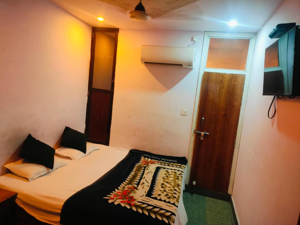 a small room with a bed and a door at Hotel Ayodhya Palace in Farrukhābād