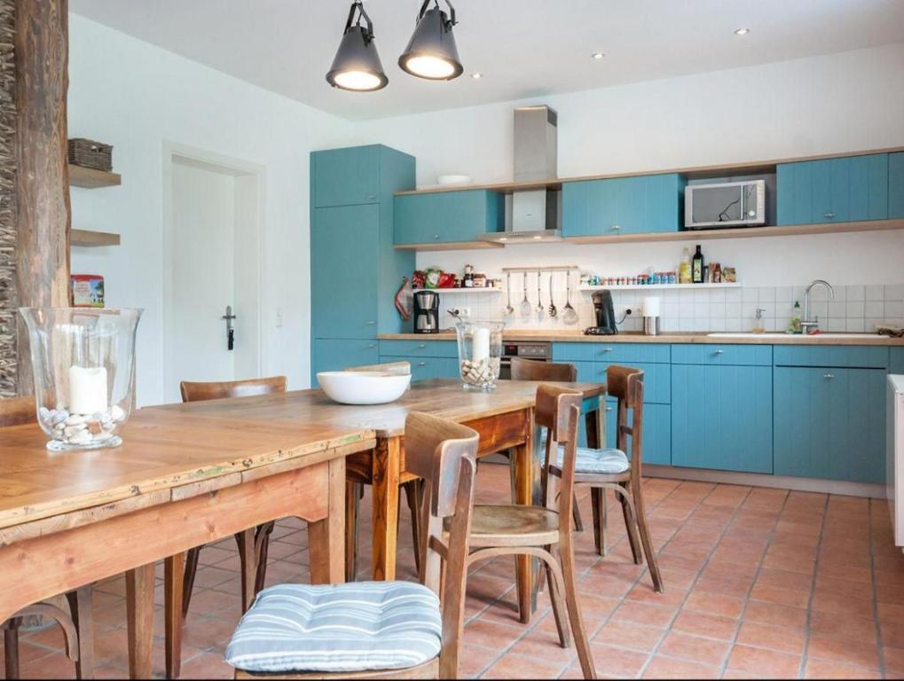 una cucina con mobili blu e un tavolo e sedie in legno di Kleine Freiheit EG bis 6 Pers a Kopendorf